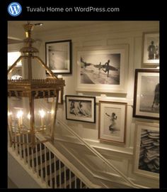 there is a stairway with pictures on the wall next to it and a light fixture