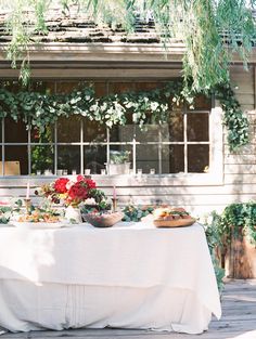 a table with food on it and flowers in front of a house that has ivy growing over the windows