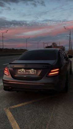 the back end of a car parked in a parking lot at dusk with its lights on