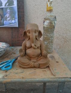 an elephant statue sitting on top of a wooden table next to a bottle and scissors