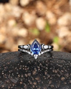 a close up of a ring with a blue and white stone in the center on a rock