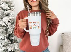 a woman holding a white coffee mug in front of a christmas tree with butterflies on it