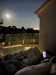 a person laying in bed with a cell phone on their lap looking at the night sky