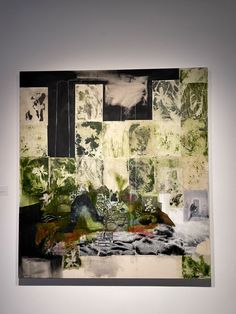 an abstract painting on display in a white walled room with black and green artwork hanging from the wall