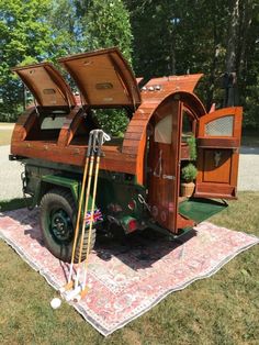 an old green truck with open doors sitting on top of a rug in the grass