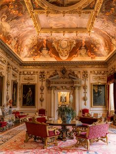 an ornately decorated dining room with red chairs and paintings on the wall above it