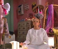 a woman sitting in the middle of a room with many decorations on the walls and floor