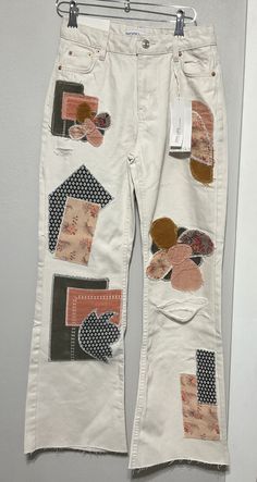 a pair of white jeans with patches on them