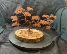 a small tree is sitting on top of a wooden plaque that has been carved into it