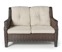 a wicker loveseat with beige cushions on an isolated white background