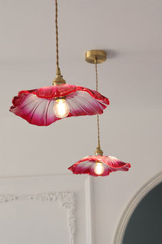 two pink flowers hanging from the ceiling in a room with white walls and gold fixtures