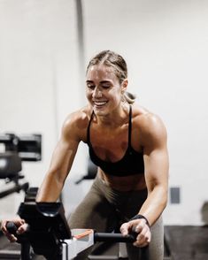 a woman working out on an exercise bike in a gym with no clothes and smiling at the camera