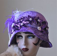 Women's cloche hat in a vintage 1920s Great Gatsby style.  A hat fancy enough for a wedding or any glitzy evening event.  The buckram hat is covered in a crushed purple velvet fabric that has been embellished with lots of sequins, pearls and feathers.    This hat is available in a SIZE MEDIUM (22 to 22 1/2")   How to measure your head.... Take a cloth measuring tape around the back of your head and over your ears. Have the tape meet on your forehead where you want the hat to sit. Do this several times as an accurate measurement is important.  Hats are 100% handmade using traditional tailoring techniques and the highest quality fabrics, hand sewn lining and details. FREE SHIPPINGby Priority mail is included.  Return shipping will be at buyers expense.  All refunds will be sent excluding the Vintage Fitted Hat For Costume Party, Flapper Hats For Kentucky Derby Party, Flapper Style Hat For Kentucky Derby Party, Gatsby Mini Hat For Kentucky Derby, Gatsby Style Party Cloche Hat With Short Brim, Flapper Style Fascinator For Kentucky Derby Evening, Gatsby Style Cloche Hat With Short Brim For Party, Flapper Style Evening Fascinator For Kentucky Derby, Gatsby Style Short Brim Cloche Hat For Party