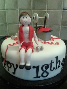 a birthday cake with a man sitting on it's side holding a barbell