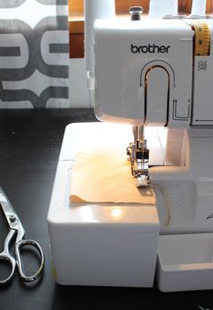 a sewing machine sitting on top of a table next to scissors and threading needles