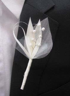 a boutonniere with white flowers and pearls on it's lapel