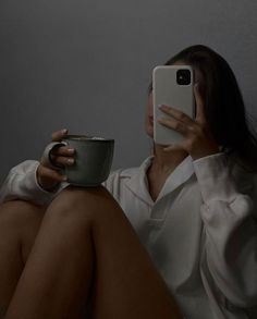 a woman is taking a selfie with her cell phone while holding a coffee cup