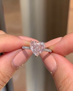 a woman's hand holding a heart shaped diamond