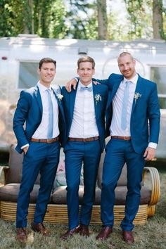 three men in blue suits and white shirts posing for a photo with their arms around each other