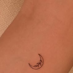 a small crescent tattoo on the back of a woman's left arm and leg