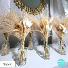 three vases with dried flowers in them sitting on a shelf next to a mirror