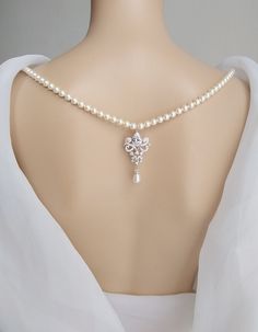 a woman wearing a white dress with a cross on it's neck and pearl necklace