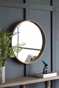 a mirror sitting on top of a wooden table next to a potted green plant