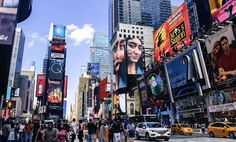 a busy city street filled with lots of tall buildings and people walking across the street