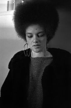 a woman with an afro is looking down at her cell phone while wearing ear rings