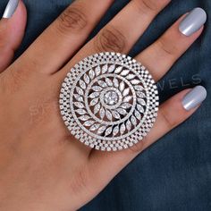 a woman's hand holding a ring with diamonds on it and two other manicured nails