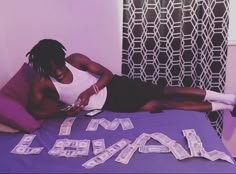 a man laying on top of a purple bed covered in money next to the words i'm legal