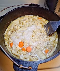 a pot filled with food sitting on top of a stove next to a spatula