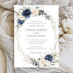 an elegant wedding card with blue flowers and greenery