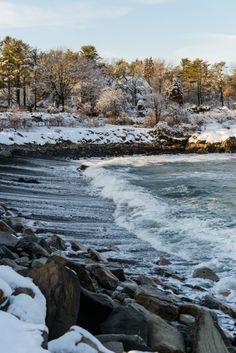 there is snow on the rocks by the water