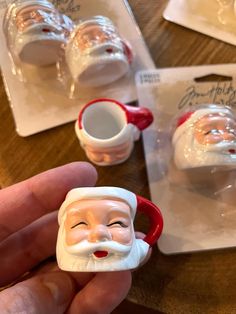 a hand holding a small plastic santa clause cup with two cups in front of it