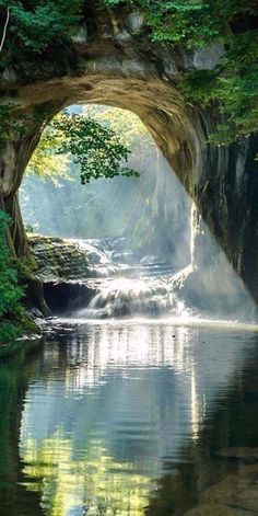 a river flowing under a bridge next to a lush green forest