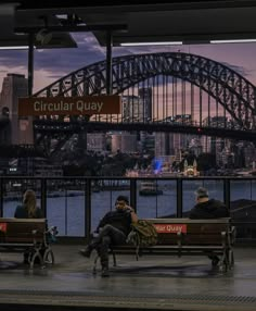 people sitting on benches in front of the sydney harbour bridge and opera house at dusk