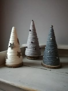 three small christmas trees sitting on top of a white mantle next to a window sill