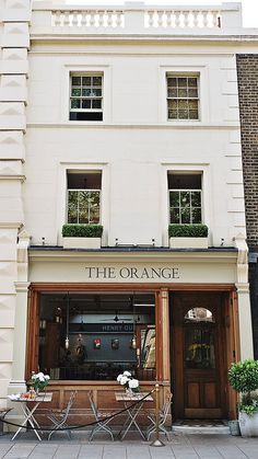 an orange store front with tables and chairs in front of the building's entrance