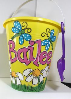 a yellow bucket with the word barbiee painted on it and flowers in the bottom