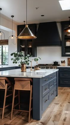 a kitchen with blue cabinets and wooden floors is pictured in this image, there are three stools at the center of the island