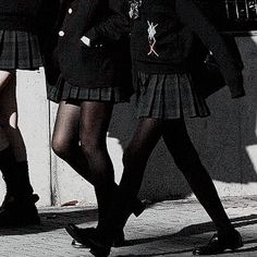 two girls in school uniforms are walking down the street with their hands on their hips