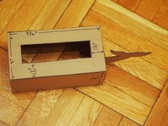 an open cardboard box sitting on the floor with a pair of scissors sticking out of it