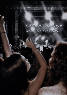 two women at a concert raising their hands in the air