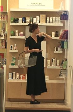 a woman standing in front of a store display holding a basket and looking at the wall