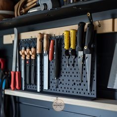 there are many different tools hanging on the pegs in this garage organization system, including knives and pliers