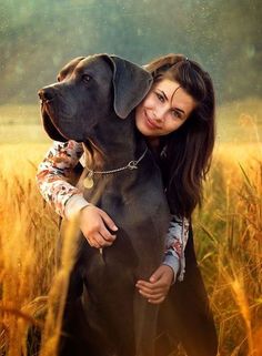 a woman hugging her dog in the middle of a field