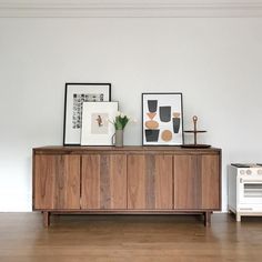 two framed pictures sit on top of a wooden cabinet