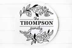 the personalized family name sign is shown on a white wood paneled wall with black and white flowers