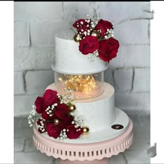 three tiered wedding cake with red roses and baby's breath in the middle